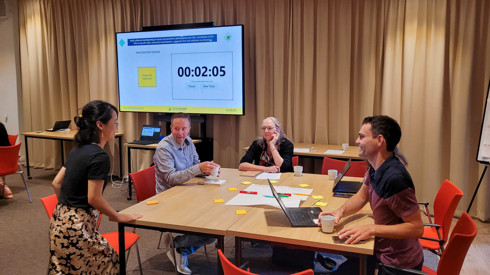 A group of people engaged in discussion around a table in a meeting room.