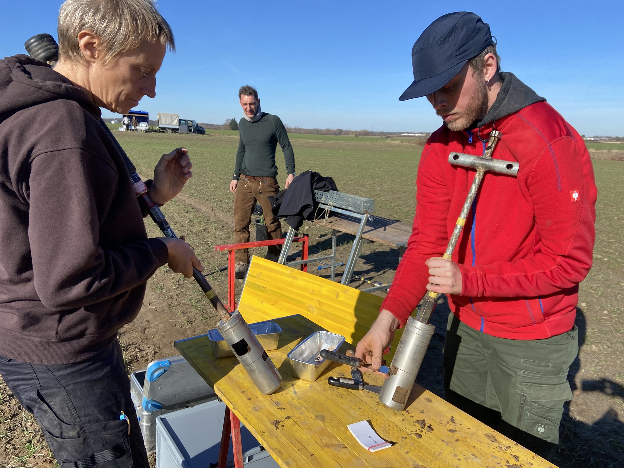 Researchers processing soil samples at an outdoor table.